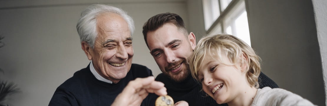 Happy watchmaker showing clockwork to young man and boy