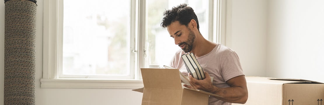 A seated man places books in a cardboard box
